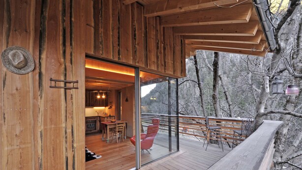 Eine Holzhütte mit einer Glastür, die zu einem Essbereich mit Tisch und Stühlen führt.