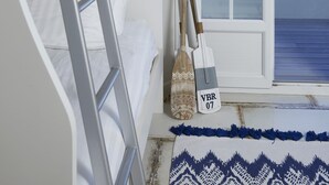 Een stapelbed met een ladder, een raam met uitzicht op het strand en een decoratieve vaas.