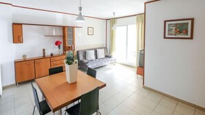 Een moderne woonkamer met een bank, een eettafel met stoelen, een televisie en een schilderij aan de muur.
