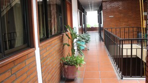 A corridor with a brick wall, potted plants, and a metal railing. - Hotel Elimar (Girardot)