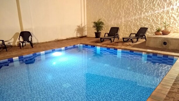 An indoor swimming pool with blue tiled flooring, surrounded by lounge chairs and potted plants. - Hotel Elimar (Girardot)
