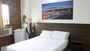 A hotel room with a large bed, a night view of the Eiffel Tower, a brick wall, and a small table with a lamp. - Hotel Elimar (Girardot)
