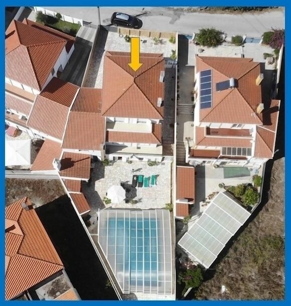 A residential area with multiple houses, each featuring red-tiled roofs and solar panels.
