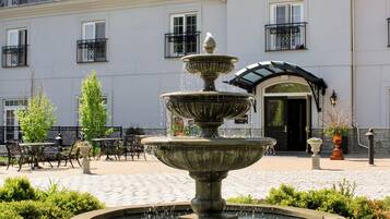 A courtyard with a fountain, outdoor seating, and a building with multiple windows and balconies.