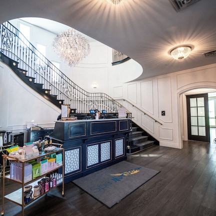 A grand staircase with a chandelier, a bar area, and a wooden floor.