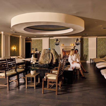 A spa room with massage tables, wooden chairs, and a central fountain.