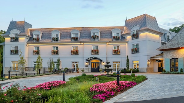 A large, multi-story hotel with a symmetrical facade, multiple balconies with flower boxes, and a central entrance with a fountain.