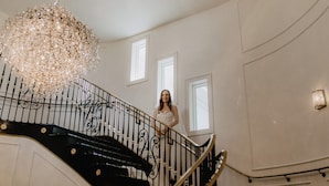 A staircase with ornate black railings and a large chandelier.