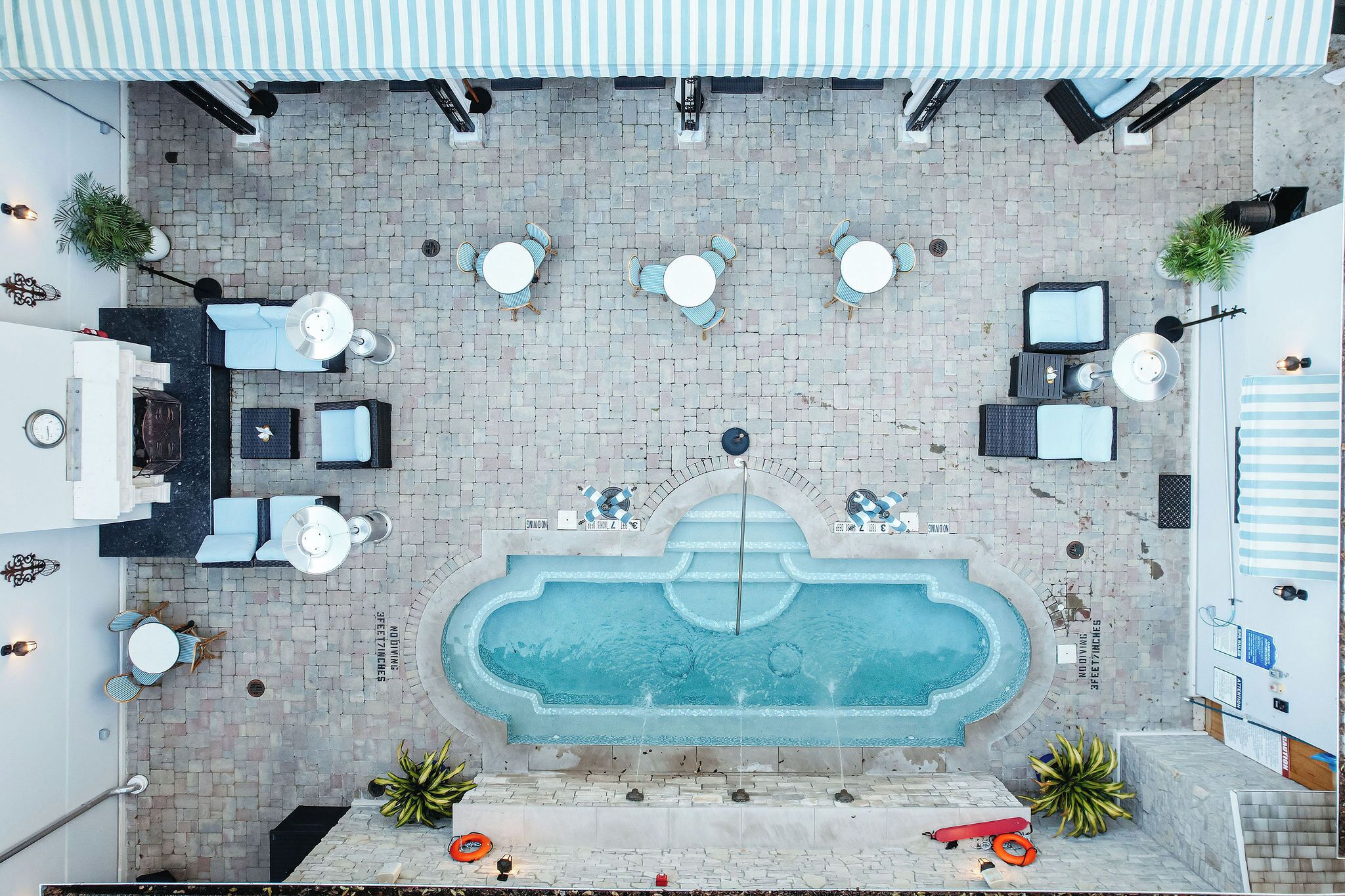 Un espace piscine aménagé sur le toit, doté de plusieurs coins salon et d’une fontaine centrale.