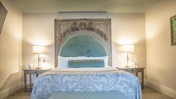 Una habitación de hotel con una cama grande, dos mesitas de noche y un cabecero decorativo.