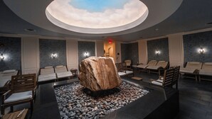 A spa area with a large rock centerpiece, multiple seating areas, and a skylight ceiling.