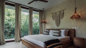 A bedroom with a large bed, wooden headboard, and a view of greenery outside. - Gated Jungle Lounge • Wabi Sabi Chic Two -Level Penthouse + Private Plunge Pool  (Tulum)