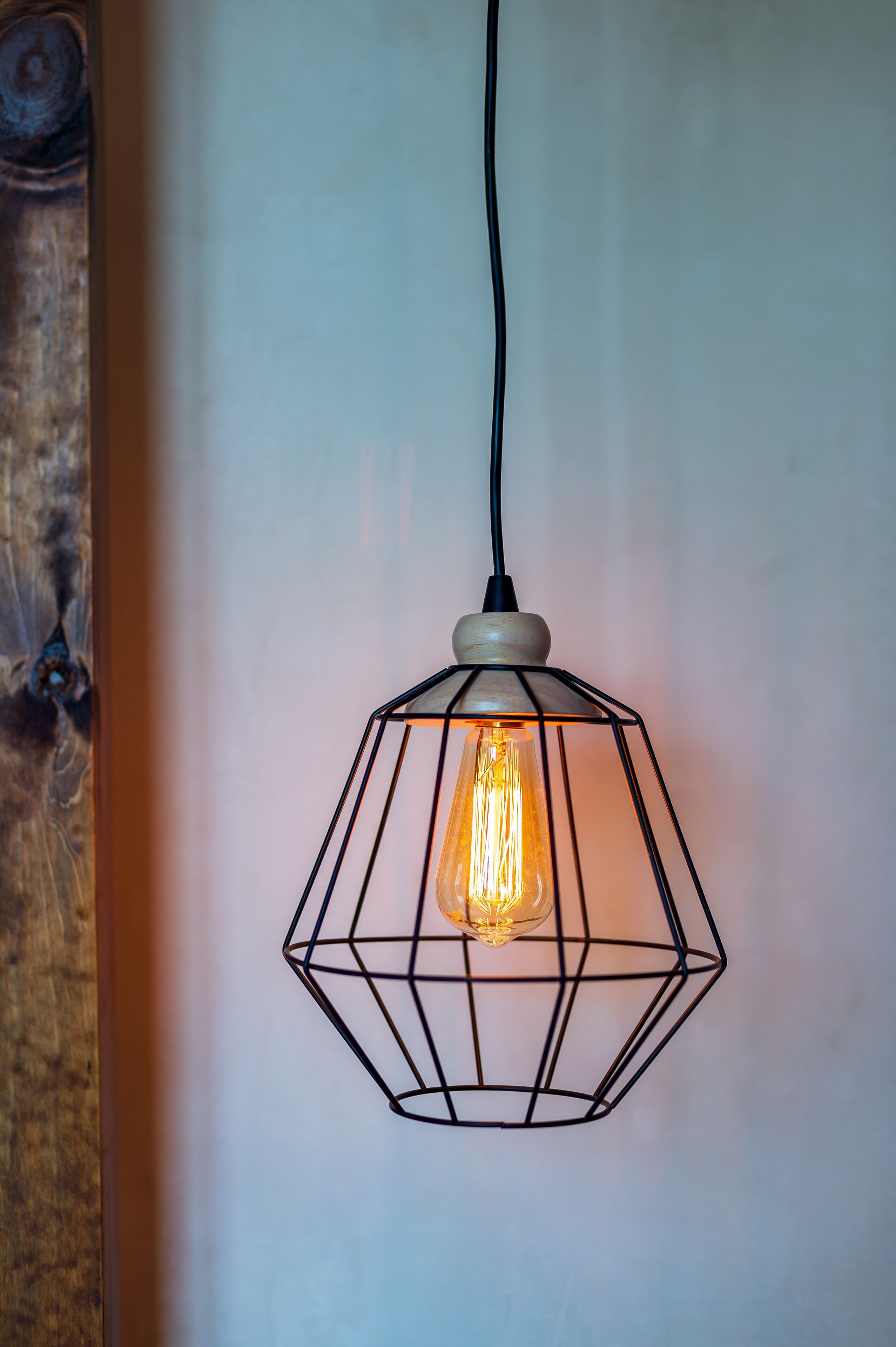 A hexagonal pendant light with a visible filament bulb hanging from a black cord.