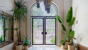 A doorway with a decorative glass door, surrounded by potted plants and a tiled floor. - Gated Jungle Lounge • Wabi Sabi Chic Two -Level Penthouse + Private Plunge Pool  (Tulum)