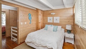 Un dormitorio con paneles de madera, una cama, mesitas de noche, un aparador y un adhesivo mural con forma de gato.