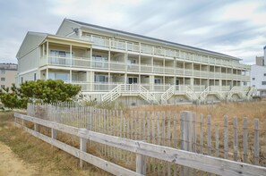 Ein mehrstöckiges Hotel mit Balkonen und einem Holzzaun im Vordergrund.
