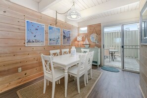 Ein Essbereich mit einem weißen Tisch und Stühlen, Holzwänden und gerahmten Bildern an der Wand.