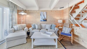 Una sala de estar acogedora con un sofá blanco, una mesita de centro y una escalera de madera.
