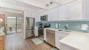 Una cocina moderna con armarios blancos, electrodomésticos de acero inoxidable y un salpicadero de azulejos azules.