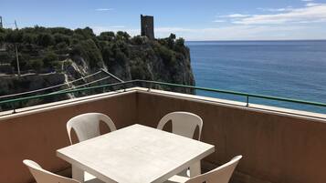 Ein Balkon mit Tisch und Stühlen mit Blick auf die Küste und einen Turm.