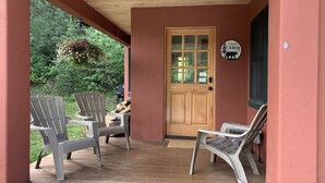 A porch with two Adirondack chairs, a wooden door, and a welcome sign. - Riverfront (600 feet), 3.65 Acres, Park Like Setting - 2 Bedroom (Durango)