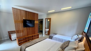 Quarto moderno com uma cama grande, TV presa a um painel de madeira, guarda-roupa e espelho.