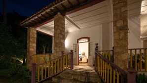 Um edifício de pedra com varanda coberta e escadaria que leva à entrada.