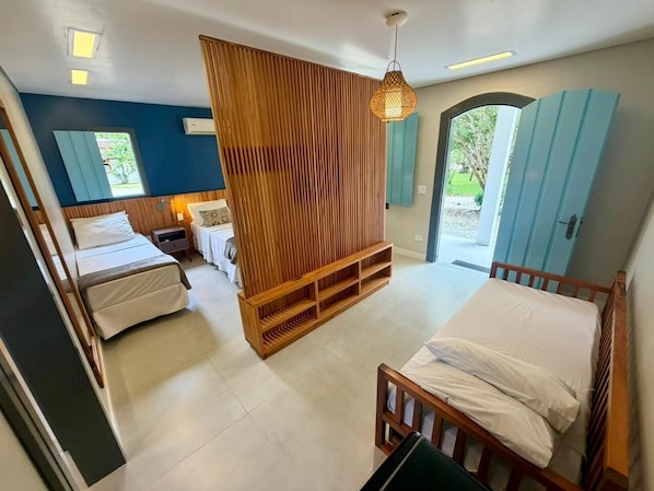 Habitación de hotel con dos camas, un separador de madera, una lámpara colgante y vistas al exterior.