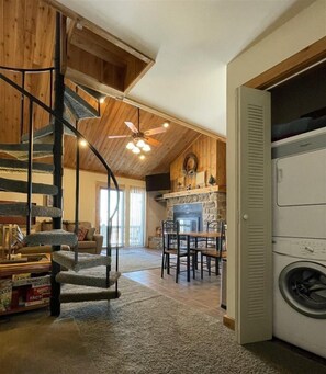 A spacious living area with a spiral staircase, a fireplace, and a laundry room. - Northwoods C3 (Davis)