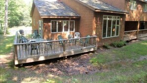 A wooden cabin with a deck, large windows, and a chimney. - Serenity (Davis)