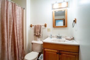 A bathroom with a toilet, sink, mirror, and shower curtain.