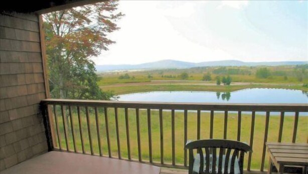 A covered outdoor area with a view of a lake and distant hills.