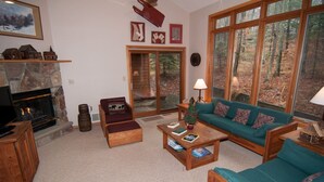 Un salón acogedor con chimenea de piedra, un sofá verde y un televisor sobre un mueble de madera.