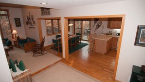 Amplia sala de estar con una mesa y sillas de comedor, una cocina con armarios de madera y un ventanal que proporciona luz natural.