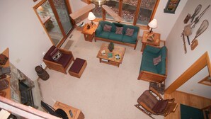 Una sala de estar acogedora con un sofá verde, una mesa de centro de madera y una chimenea.