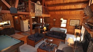 A cozy log cabin interior with a pool table, sofas, and a fireplace. - Mingo Lodge (Davis)