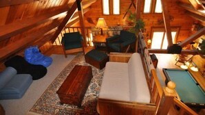 A cozy attic room with wooden beams, a pool table, and a sofa. - Mingo Lodge (Davis)