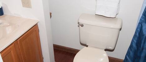 A small bathroom with a toilet, sink, and wooden cabinet.