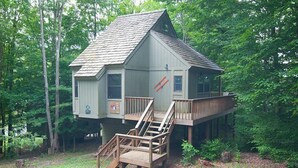 Une cabane dans les arbres dotée d’une terrasse en bois et d’un escalier menant à un palier.