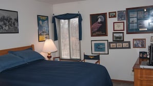 Une chambre à coucher avec un grand lit, un bureau et divers tableaux encadrés accrochés aux murs.