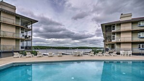 A swimming pool with lounge chairs and a view of a multi-story building with balconies. - Pool Access + Private Deck: Lake Ozark Retreat (Lake Ozark)