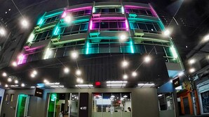 Een eetruimte met tafels en stoelen, een modern gebouw met kleurrijke verlichting, en een zichtbare ingang.