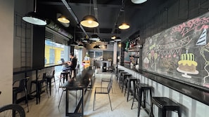 An interior with a long counter, multiple stools, and a chalkboard with drawings. - Graffi City House (Florianópolis)