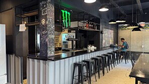 Una zona de bar con taburetes, mostrador y un refrigerador.