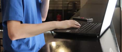 Una persona sentada a una mesa con una computadora portátil, sosteniendo una taza.