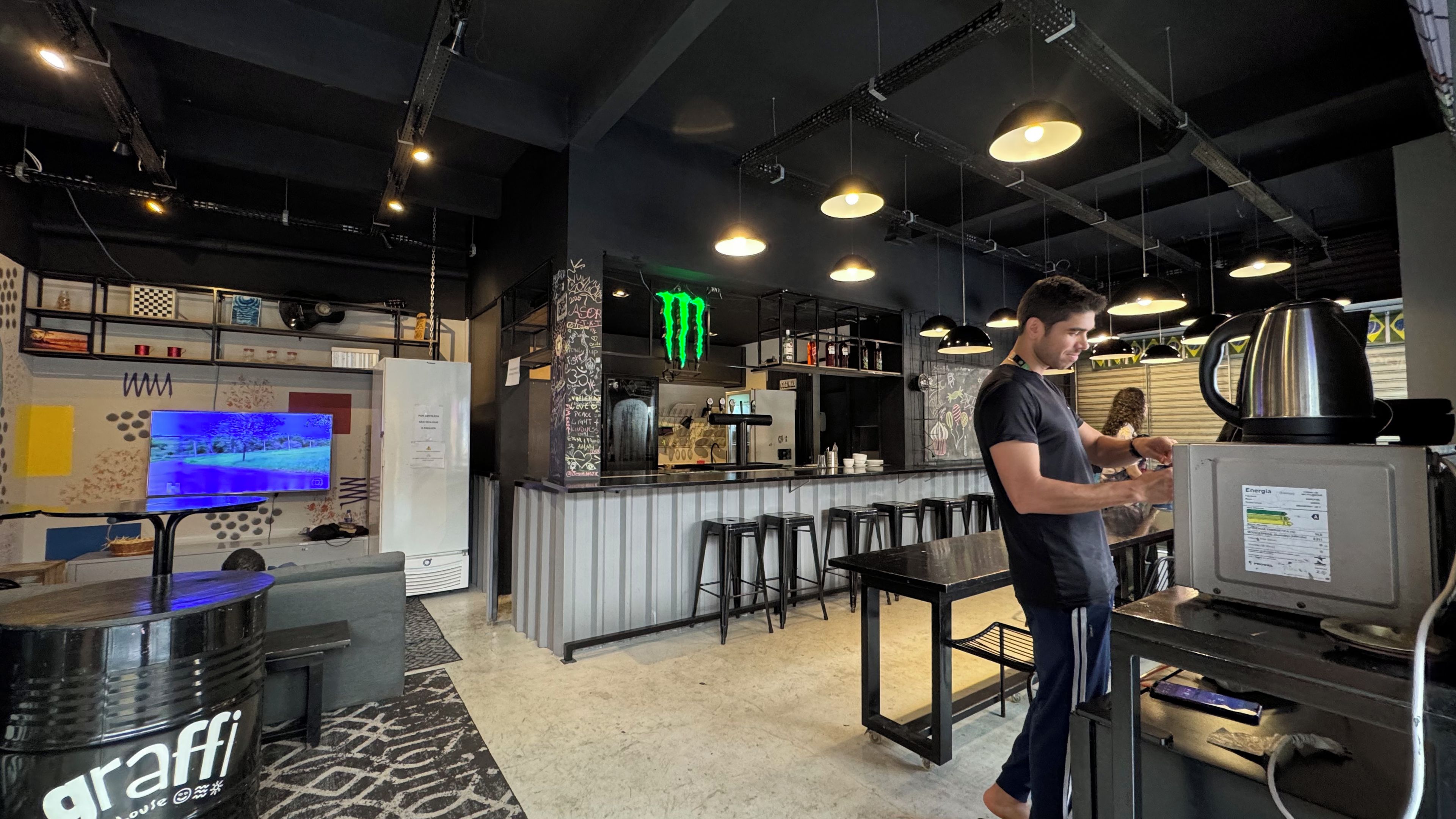 A bar area with stools, a television, and a refrigerator.