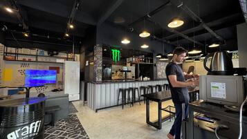 A bar area with stools, a television, and a refrigerator.