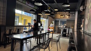 Un espace bar intérieur avec des tables et des chaises, un comptoir d’accueil et un menu écrit à la craie.