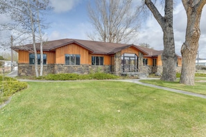 A modern two-story house with a stone foundation, wooden siding, and a brown roof.