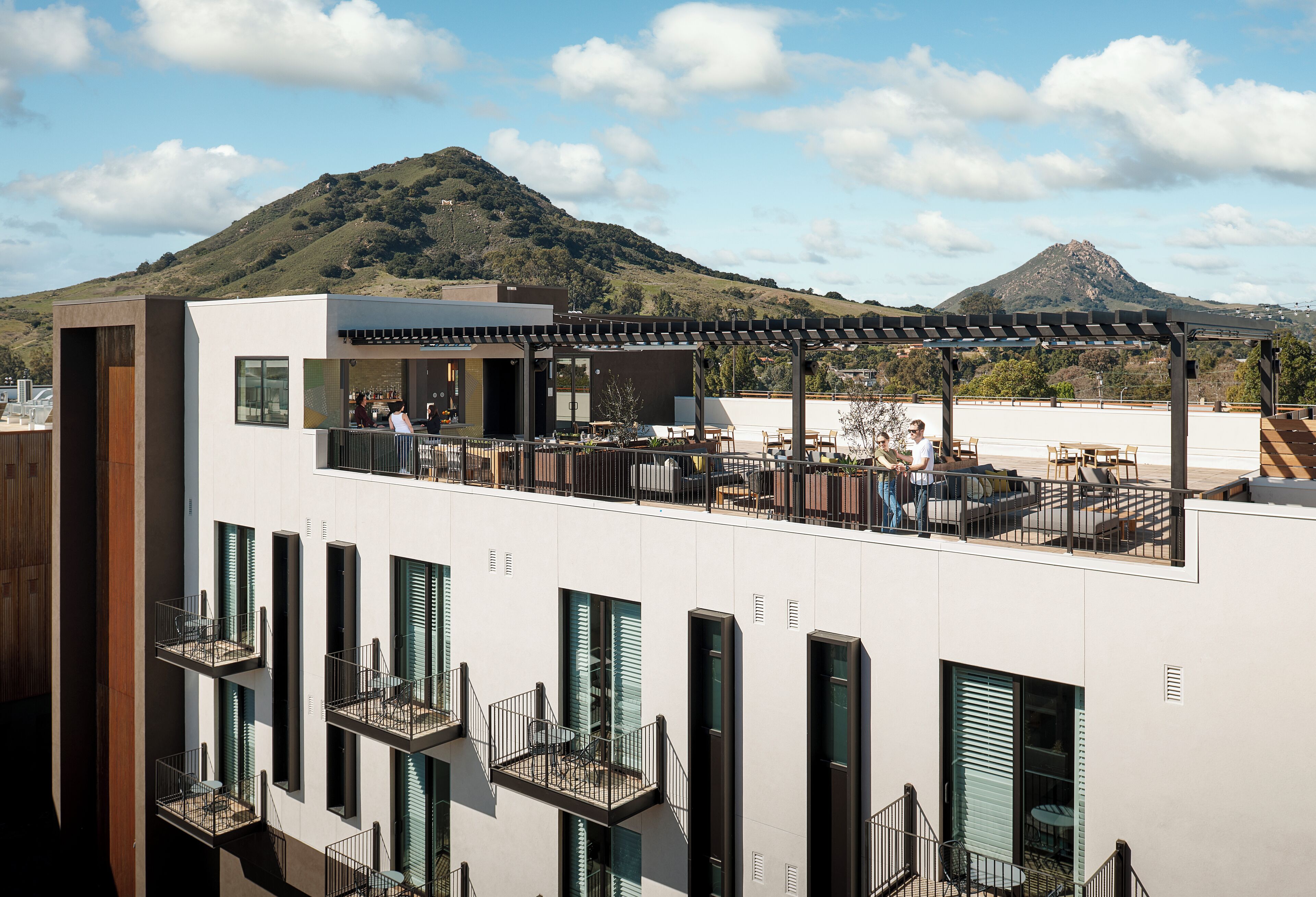 A modern building with multiple balconies and a rooftop patio area.